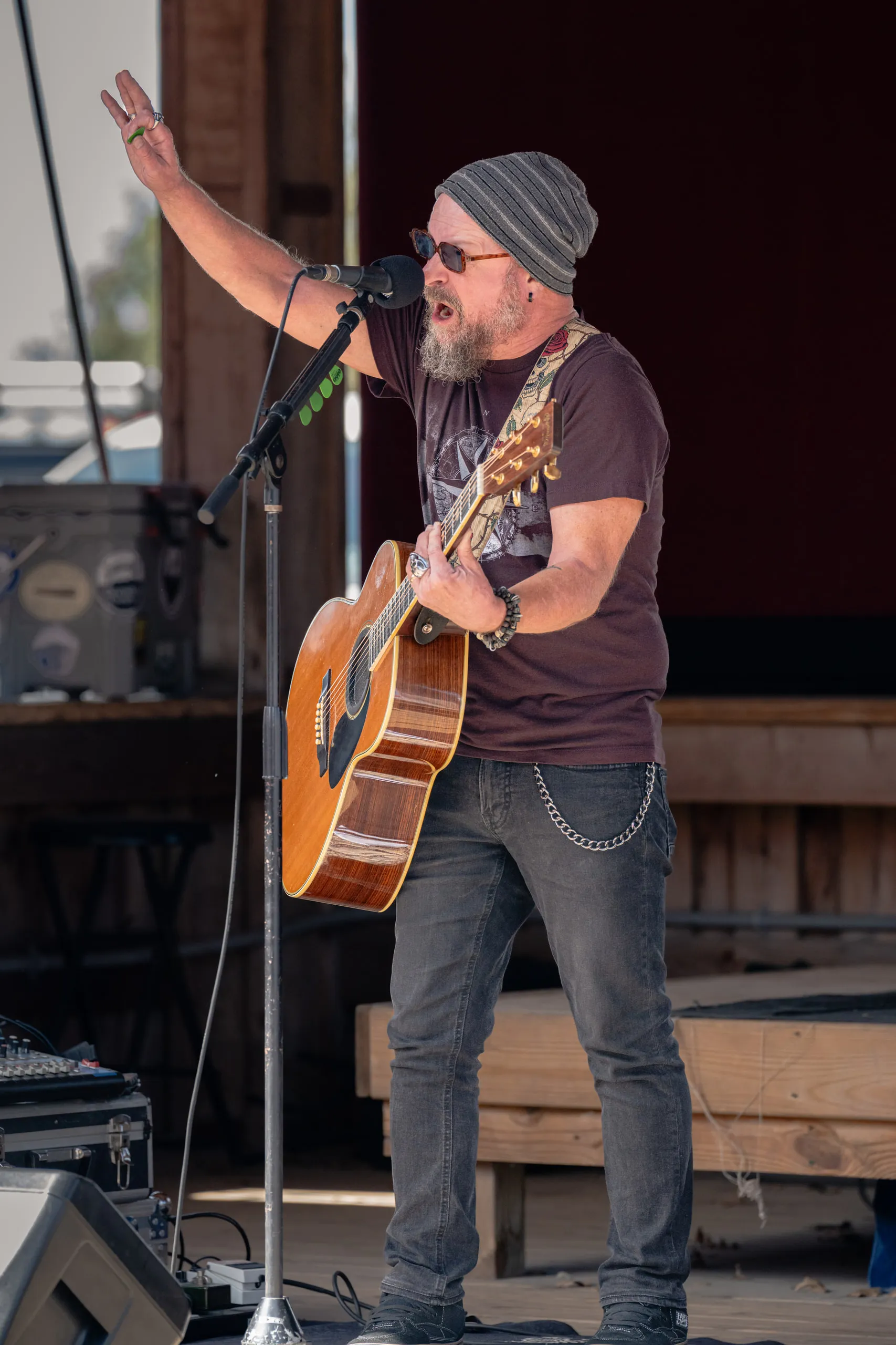 The guitarist reaches an arm overhead mid-song, leaning in to the microphone