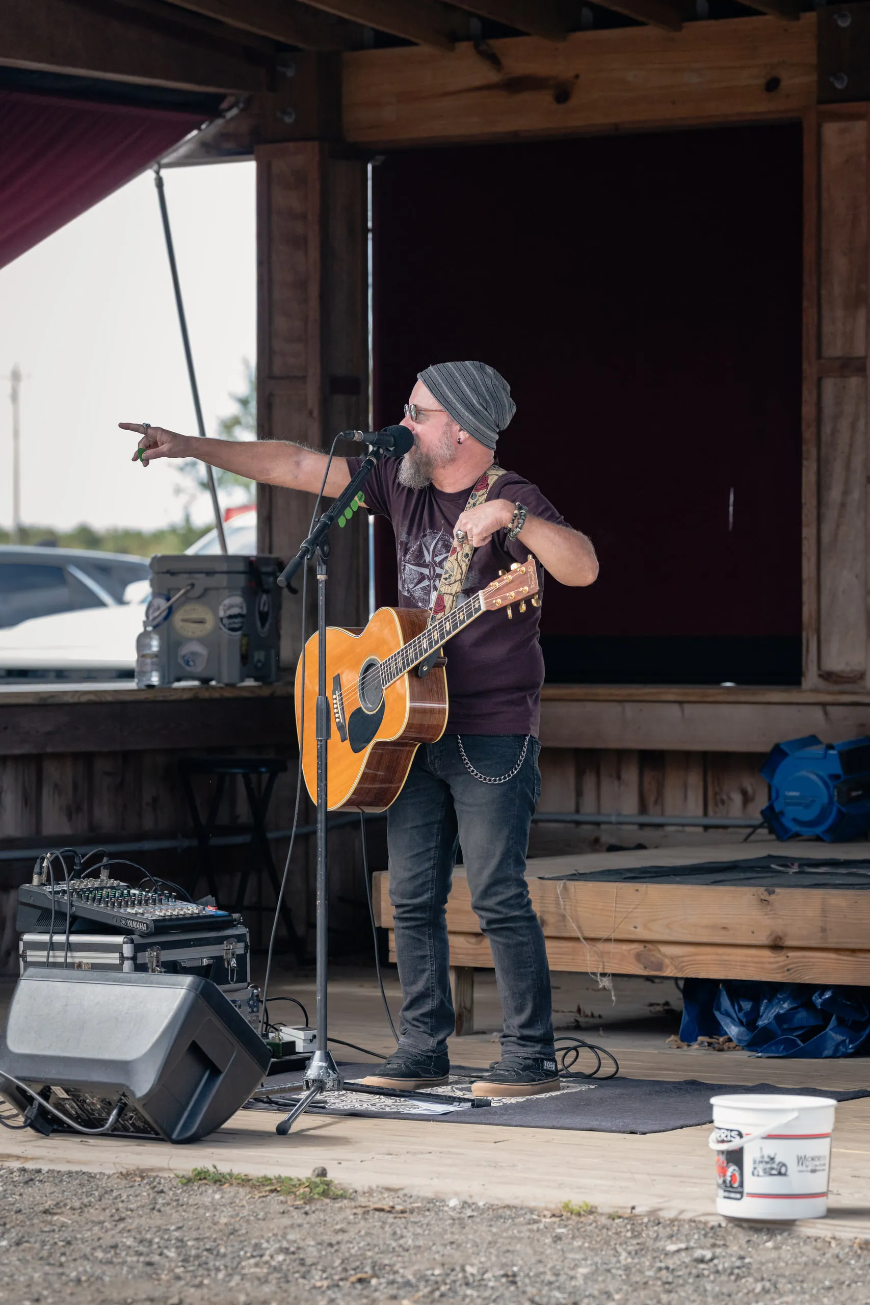 The guitarist points out past the microphone between lines, guitar held clear